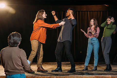 Eine Gruppe von Menschen bei einer Theaterprobe, die gemeinsam Szenen üben.