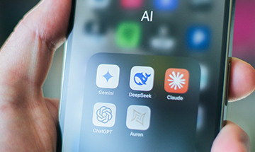 Smartphone mit geöffnetem AI-Ordner und fünf App-Symbolen: Gemini, DeepSeek, Claude, ChatGPT und Auren.