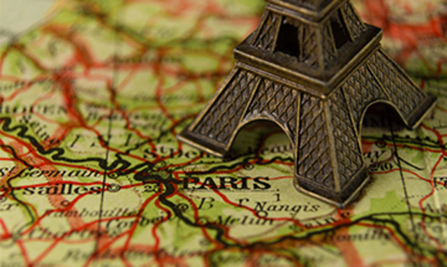 Miniatur des Eiffelturms auf einer Landkarte mit Fokus auf Paris.