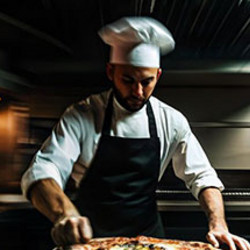 Ein Mann mit Kochmütze macht Pizza