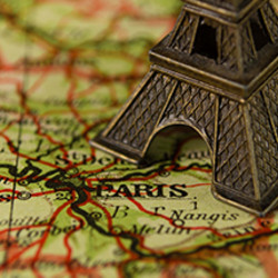 Miniatur des Eiffelturms auf einer Landkarte mit Fokus auf Paris.